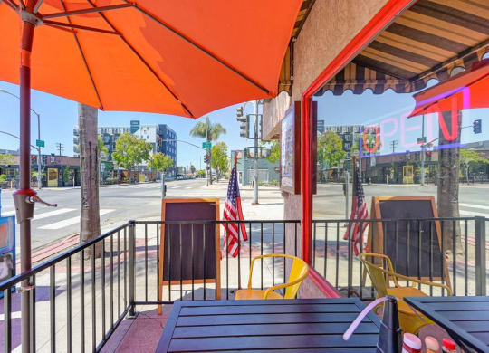 a patio with tables and chairs and an orange umbrella