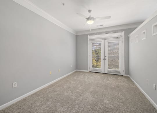 a bedroom with a ceiling fan and french doors