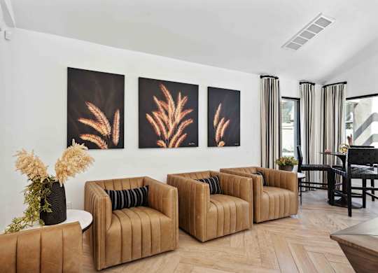 A living room with brown sofas and a painting of a plant.