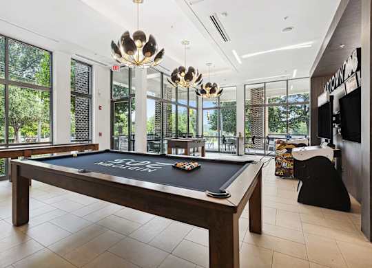 A pool table in a room with a view of trees outside the window.