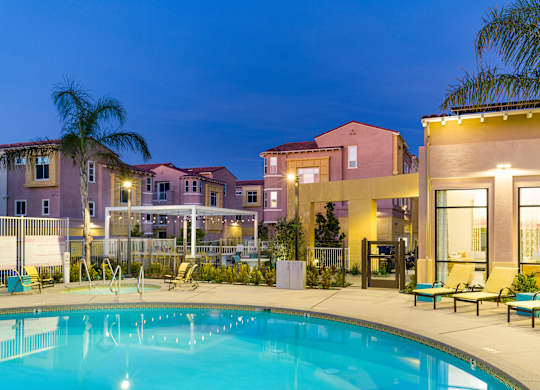 A swimming pool in front of a building with a yellow building to the right.