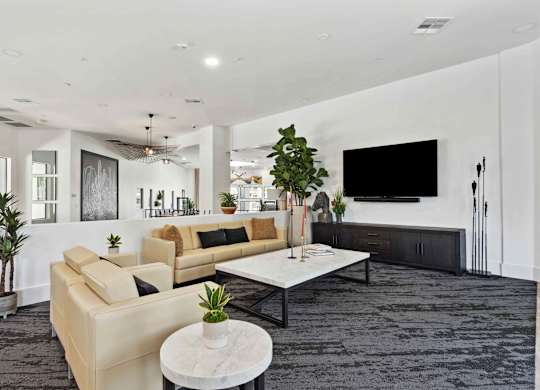 A modern living room with a large couch, a coffee table, and a flat-screen TV.