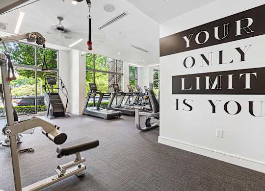 a gym with cardio equipment and a large sign that says your only limit is you