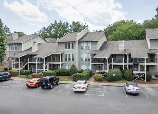the apartment complex with cars parked in a parking lot
