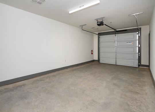 A large empty room with a white wall and a closed white door at the end.