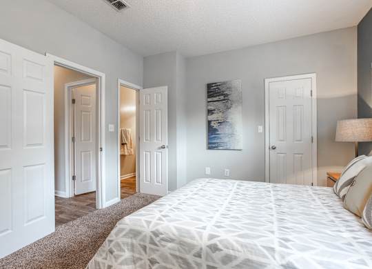 A bedroom with a large bed and a painting on the wall.