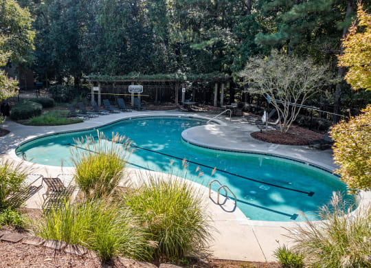a swimming pool is surrounded by trees and plants at View at Lake Lynn, Raleigh, NC