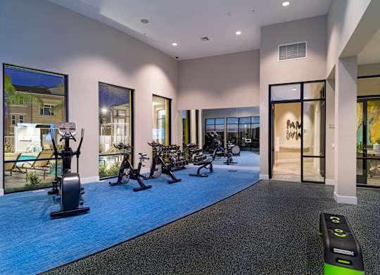 A gym with a row of exercise bikes and a row of exercise machines.