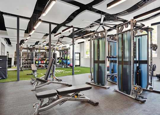 A gym with a variety of equipment including treadmills, weights, and exercise machines.