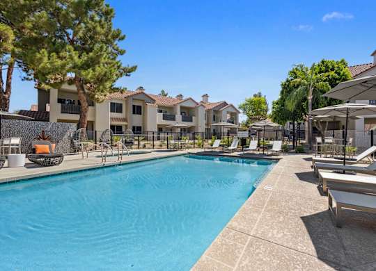 A large swimming pool surrounded by lounge chairs and umbrellas.