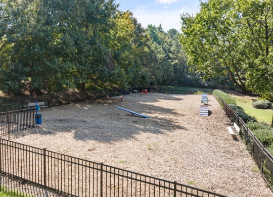 the playground is surrounded by a fence and trees at View at Lake Lynn, Raleigh, 27613