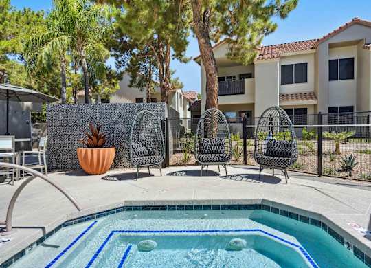 A pool surrounded by chairs and a fence with a wall in the background.