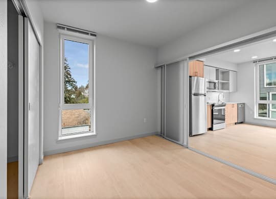 A room with a window and a kitchen area.