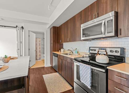 Galley kitchen with wood cabinets and white subway tile at Six Oaks Apartments, Bothell, Washington