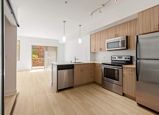 Kitchen with wood grain cabinets and stainless appliances at Six Oaks Apartments, Washington, 98011