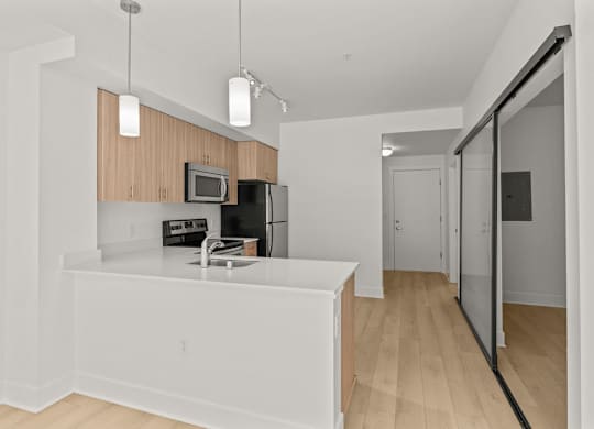 Open kitchen with white quartz countertop and peninsula at Six Oaks Apartments, Bothell, Washington