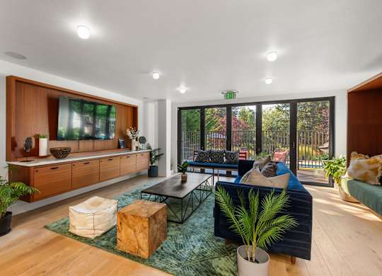 Community lounge with blue sofas and wooden entertainment center at Scout Apartments, Kirkland, Washington