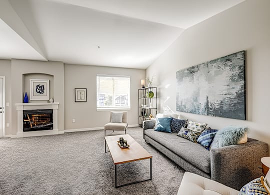 A living room with a grey couch and a fireplace.