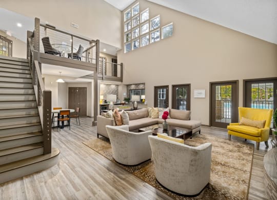 a living room with couches and chairs and a staircase