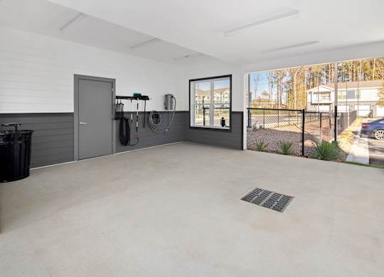 A spacious garage with a concrete floor and a black trash bin.