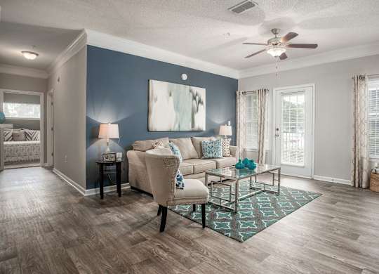 A living room with a beige couch, a coffee table, and a ceiling fan.