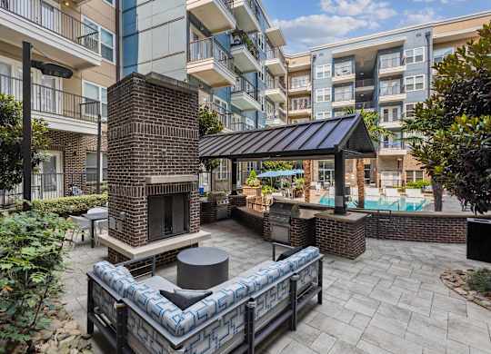 a patio with a fireplace and a pool in front of an apartment building