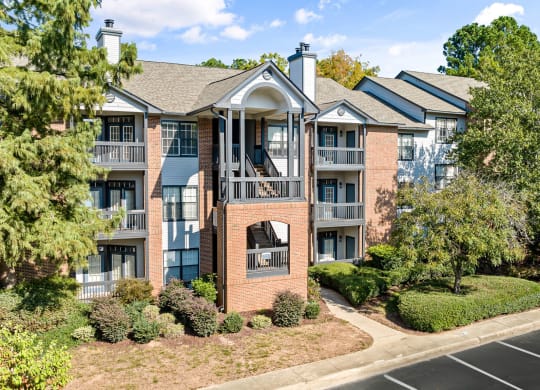 an apartment building with brick exterior and balconies with trees at View at Lake Lynn, Raleigh