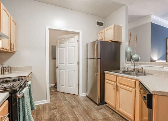 A kitchen with wooden cabinets and a black refrigerator.