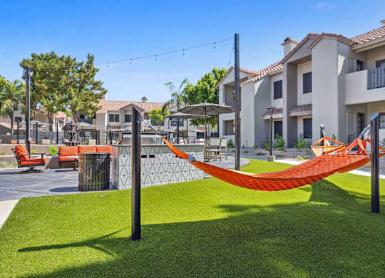 A hammock is strung between two poles in a grassy area.