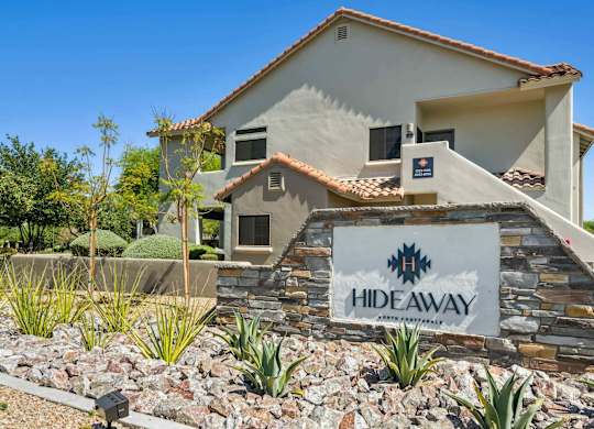 A house with a sign that says HIDEAWAY in front of it.