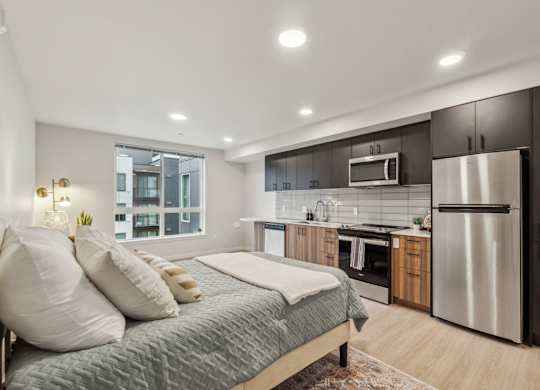 A modern bedroom with a large bed and a kitchen area in the background. at Ion Town Center, Shoreline