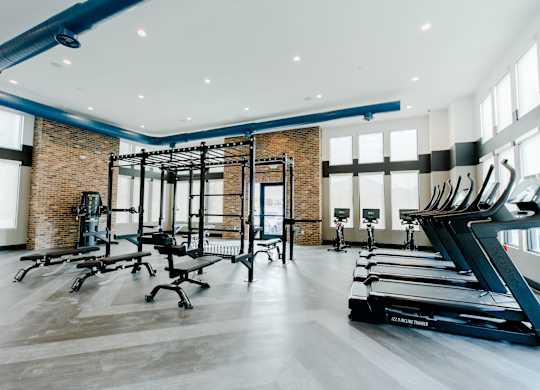 the gym has treadmills and other exercise equipment and windows