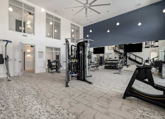 a gym with weights and cardio equipment in a building with large windows