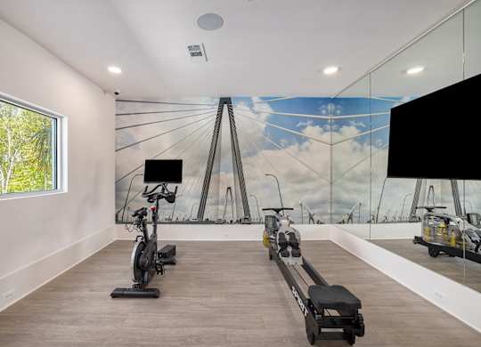 a gym with weights and a mural of a bridge on the wall