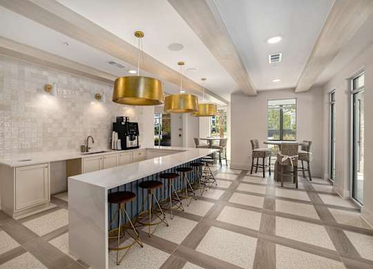 a large kitchen with a long counter and chairs and a dining table