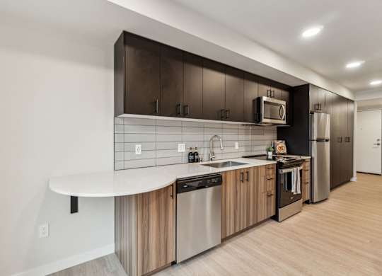A modern kitchen with a white countertop and stainless steel appliances at Ion Town Center, 98133.