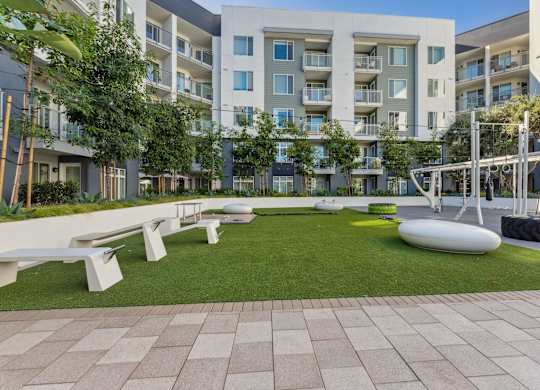 A modern apartment complex with a grassy courtyard and benches.