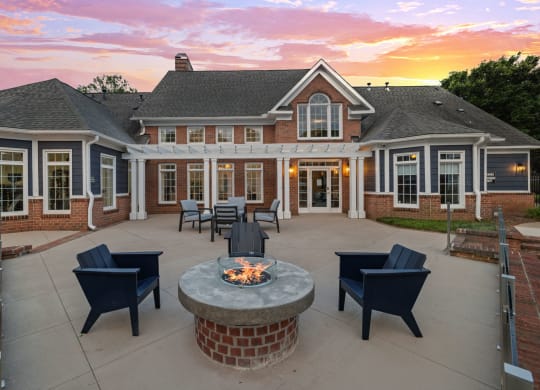 a patio with a firepit and chairs in front of a house