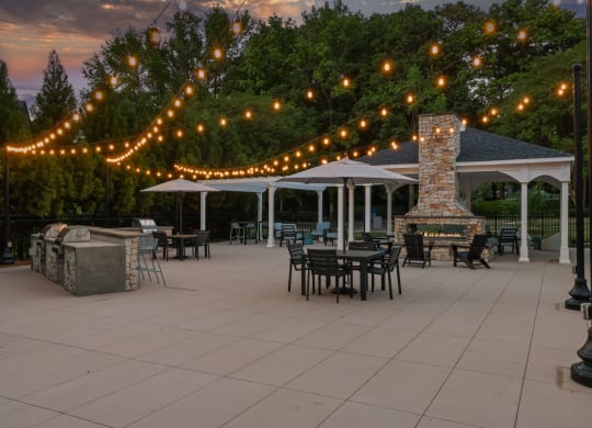 a patio with tables and chairs and strings of lights