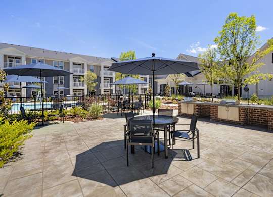 A patio with a table and chairs and umbrellas.