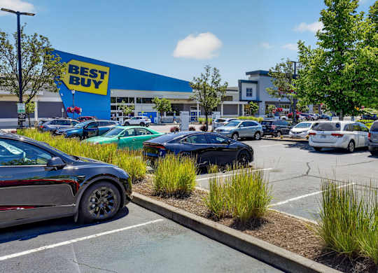A Best Buy store with cars parked in the lot.