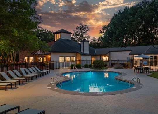a swimming pool at dusk with a house in the background