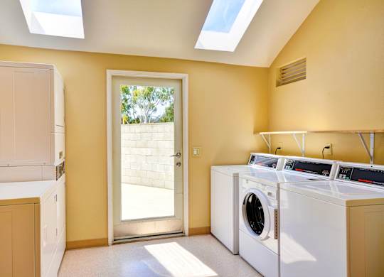 A laundry room with a washer and dryer, a door leading outside, and a skylight.