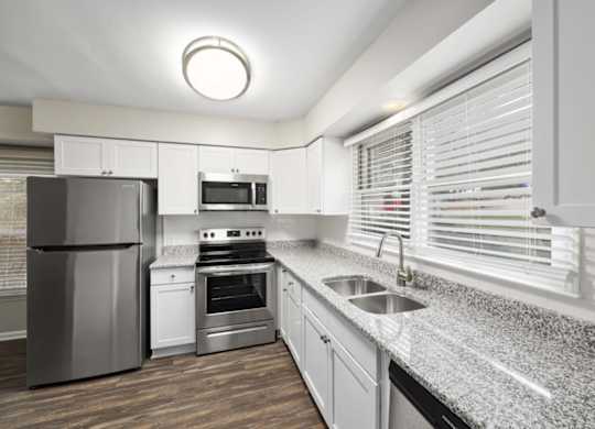 A modern kitchen with a granite countertop and stainless steel appliances.