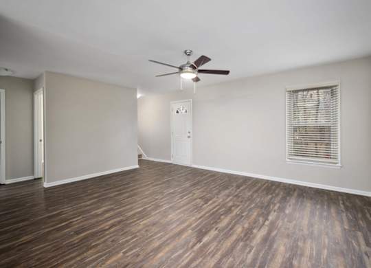 A room with a ceiling fan and wooden flooring.