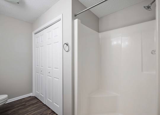 A white bathroom with a toilet and a walk-in shower.