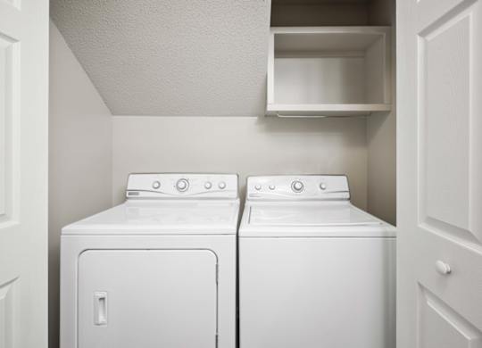 Two white front loading washing machines in a small laundry room.