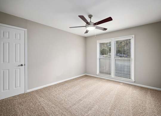A room with a ceiling fan and a window with blinds.