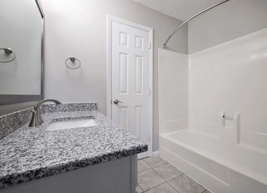 A bathroom with a granite countertop and white fixtures.