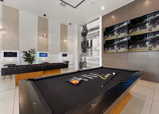A pool table with a green felt cloth and a white cue ball and red balls.